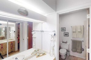 Une salle de bain avec un grand miroir, un porte-serviettes, des toilettes et un espace douche.