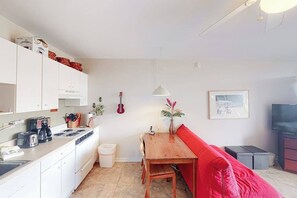 Une cuisine de taille réduite avec des meubles blancs, une table à manger et un canapé rouge.