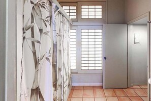 A room with a tiled floor, a door with a window, and a wall with a bamboo pattern. - NEW Fall Special Oceanfront Molokai Cottage Steps from Kepuhi Beach (Maunaloa)