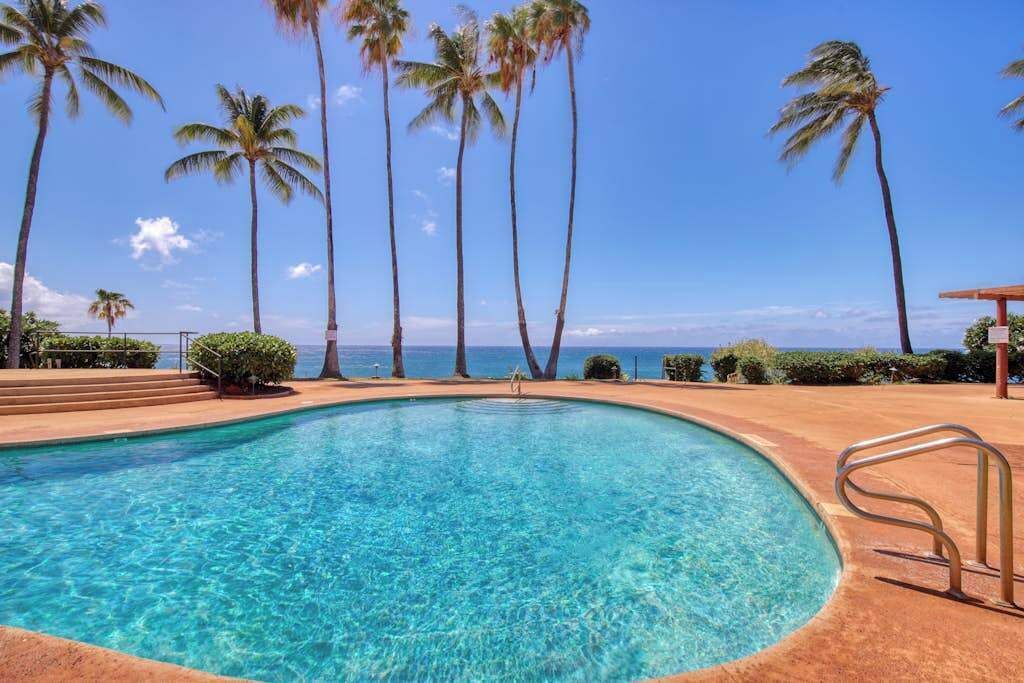 Piscina cristalina con palmeras y vista al océano.