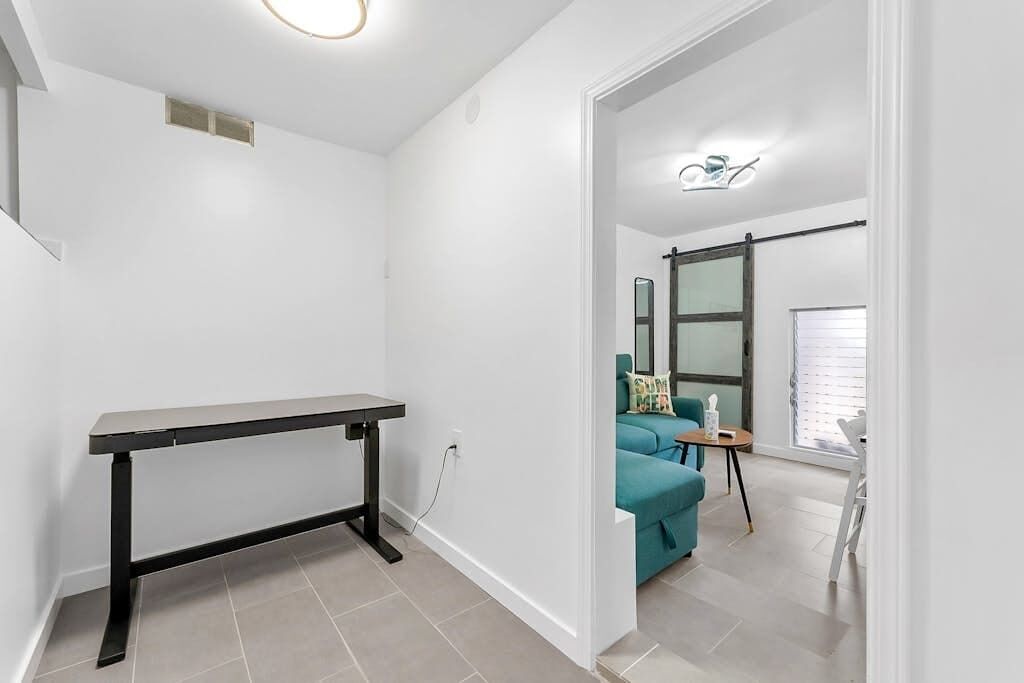 Een moderne kamer met een zwarte tafel, een smaragdgroene bank en een klein houten tafeltje met een stoel.