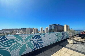 A rooftop terrace with a decorative railing, a city skyline in the background, and a clear sky. - Waikiki Studio With Expansive Views | 30 night minimum (Honolulu)