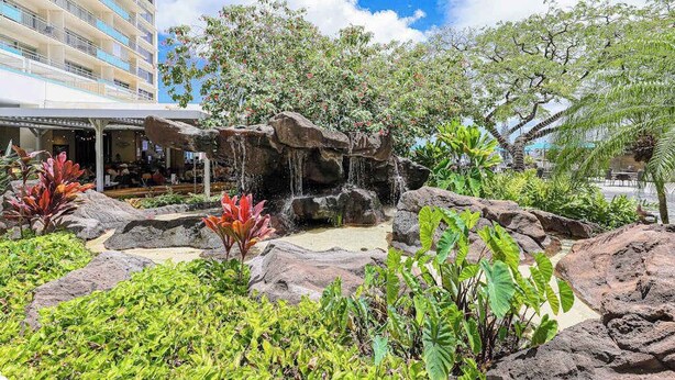 Um hotel com um jardim de pedras, uma cascata e muita vegetação.