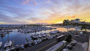 Uma marina com barcos atracados, área de estacionamento e edifícios ao fundo.