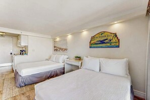 A hotel room with two beds, a desk, a small cabinet, and a wall-mounted sign. - Waikiki Studio High Rise with Lanai and Pool - 30 night minimum (Honolulu)