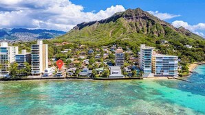 A coastal town with buildings, a mountain, and clear turquoise waters. - NEW Historic Tonggs Beach Home with Three Sunset Lanais (Honolulu)