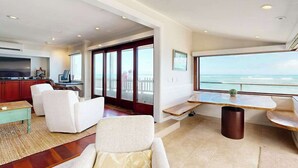 A modern living room with a view of the ocean, a kitchen area, and a dining space. - NEW Historic Tonggs Beach Home with Three Sunset Lanais (Honolulu)