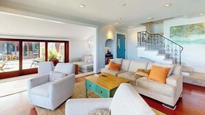 A spacious living room with a large window, a staircase, and a view of the outdoors. - NEW Historic Tonggs Beach Home with Three Sunset Lanais (Honolulu)