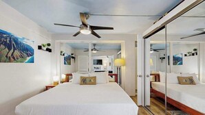 Ein modernes Hotelzimmer mit einem großen Bett, einem Deckenventilator, einem Spiegel und Blick auf den Ozean.