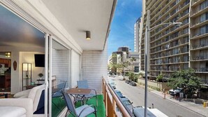 Ein Balkon mit Tisch und Stühlen, einer Couch und Blick auf eine Stadtstraße sowie Gebäude.