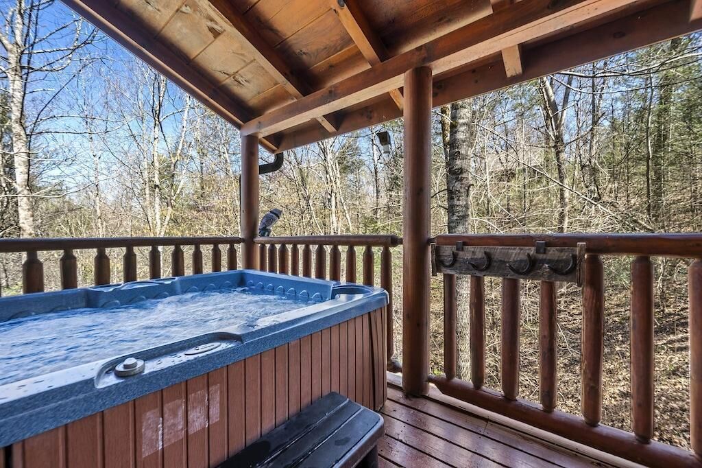 Eine Holzterrasse mit Whirlpool, umgeben von Bäumen.