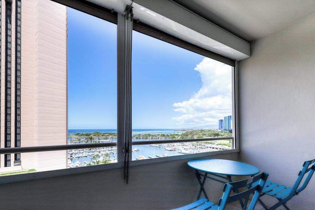 Ein Balkon mit Blick auf den Yachthafen und die umliegenden Gebäude, ein Tisch und Stühle.