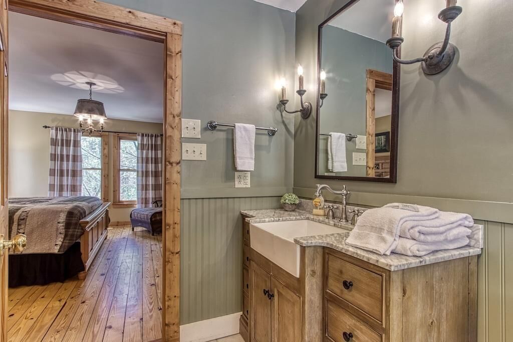 A bathroom with a wooden vanity, a mirror, and a sink.