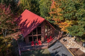 A cabin with a red roof, large windows, and a porch with red chairs. - Can't Bear to Leave (Sevierville)