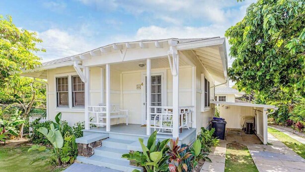 A white house with a covered porch, steps leading to the entrance, and a small garden area. - *New* Two Waikiki Cottages with Diamond Head Views | 30 Nights (Honolulu)