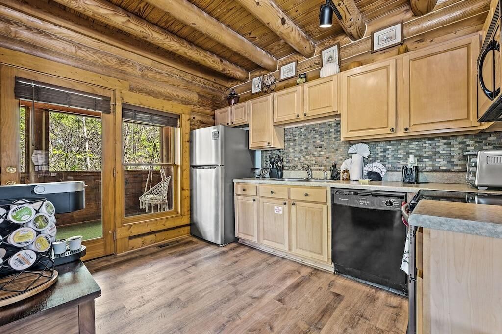 A wooden cabin kitchen with a refrigerator, dishwasher, and wooden cabinets.
