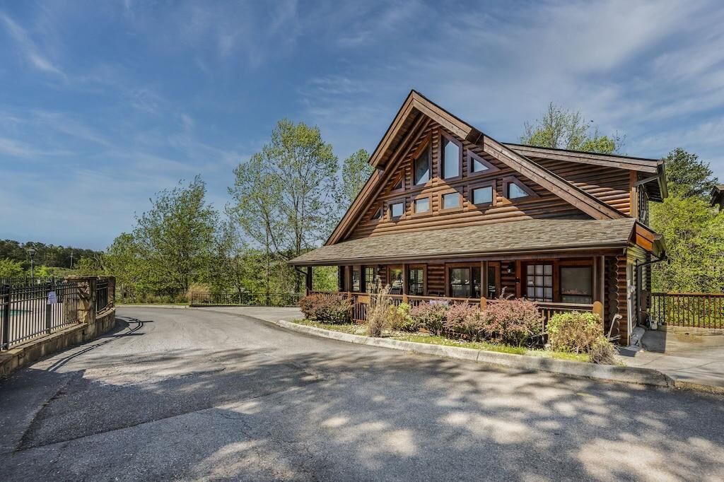 Ein Blockhaus mit markantem Satteldach, einer Veranda mit Geländer und einer Auffahrt zum Eingang.
