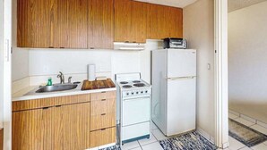 Une cuisine de taille réduite, avec des meubles de rangement en bois, une cuisinière blanche et un réfrigérateur.