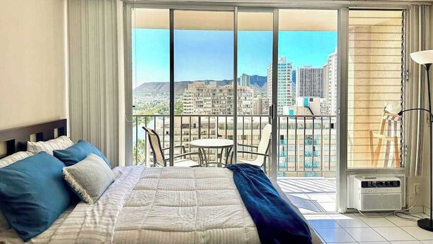 Une chambre d’hôtel avec un grand lit, un balcon donnant sur la ville et une table avec des chaises.