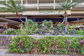 Ein Hotel namens 'Island Colony' mit einem angelegten Garten, der verschiedene Pflanzen und eine Statue zeigt.