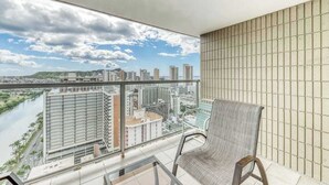 Ein Balkon mit Blick auf die Stadt, ein Sessel und ein Glastisch.