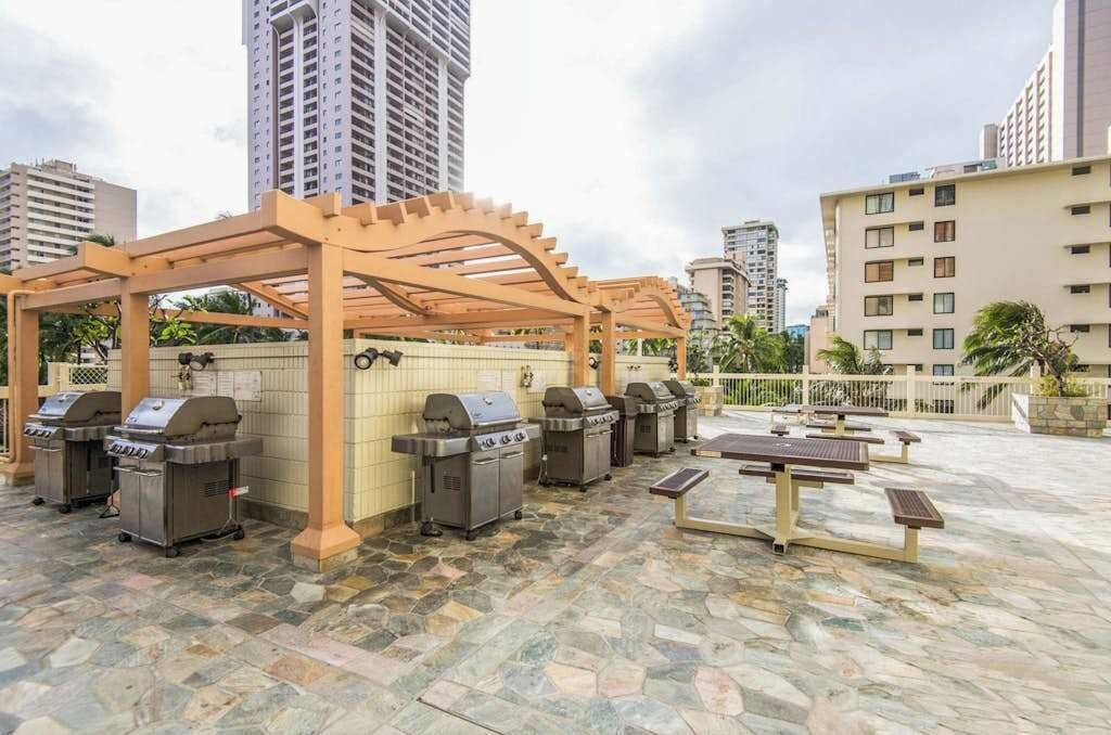 An outdoor patio area with barbecue grills and picnic tables.