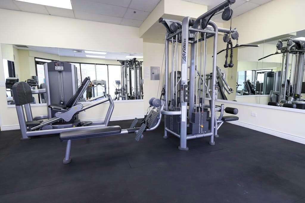 Ein Fitnessstudio mit verschiedenen Trainingsgeräten, Spiegeln und einem sauberen, gut beleuchteten Innenraum.