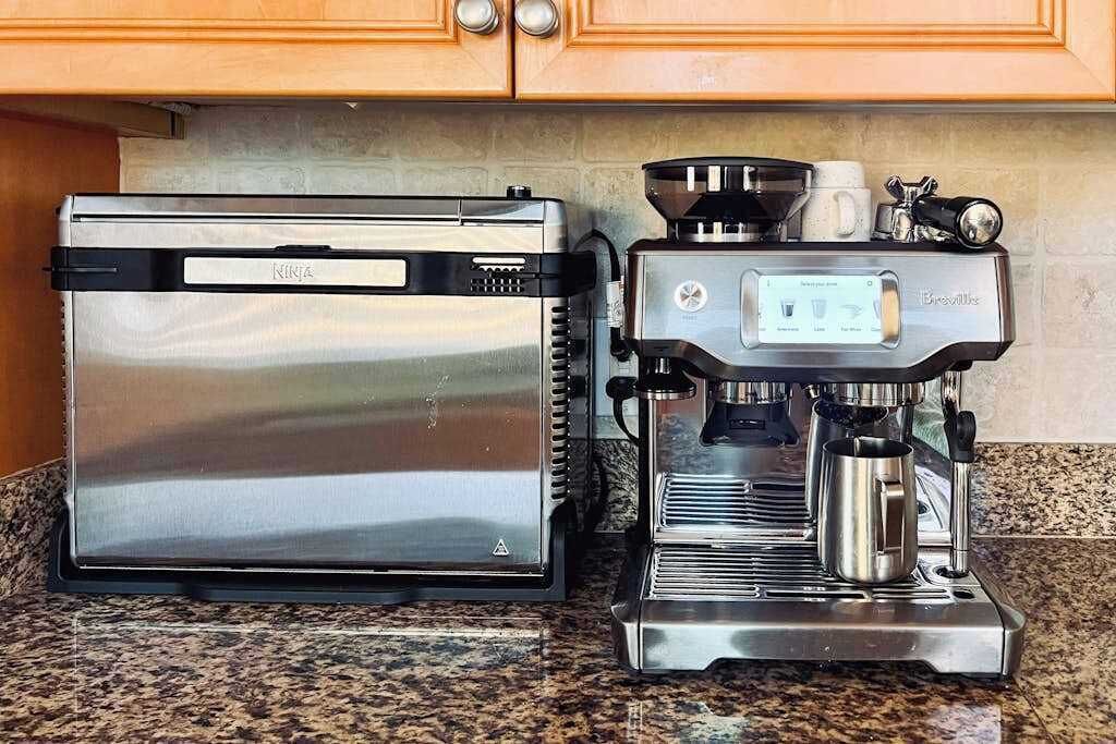 A kitchen with a stainless steel toaster and a Breville espresso machine.