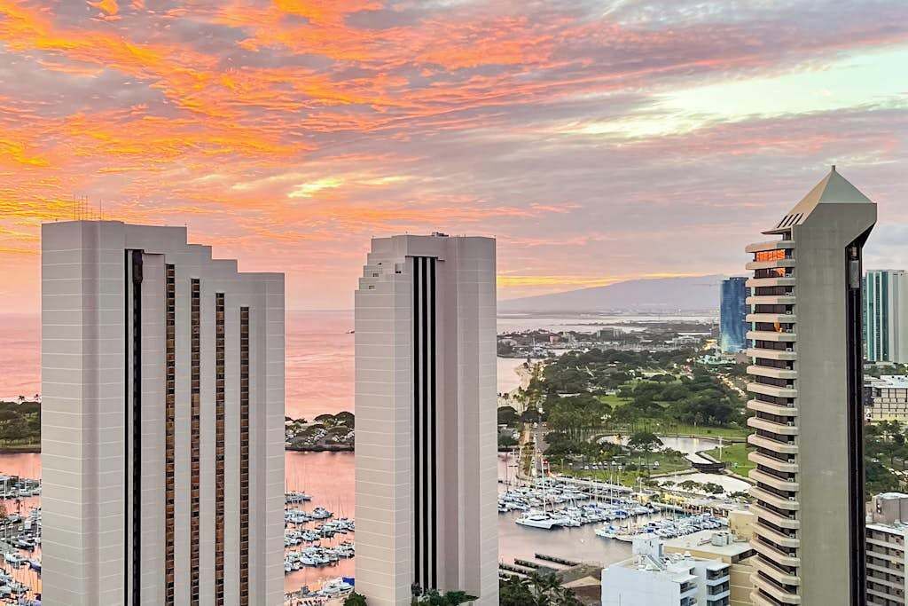 Two modern high-rise buildings with a marina and boats in the background.