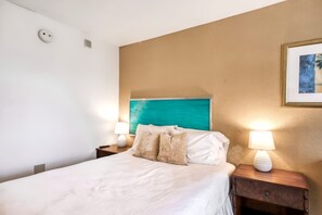 A hotel room with a bed, two bedside lamps, a headboard, and a framed picture on the wall. - New Fall $ale Waikiki Studio with City-View Balcony One Block from the Beach (Honolulu)