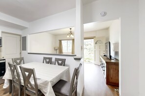 A dining area with a table and chairs, a kitchen with cabinets, and a large mirror reflecting the room. - New Garden-Quiet Honolulu Guest House with Mountain Views (Honolulu)