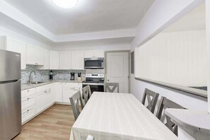 A modern kitchen with white cabinets, a stainless steel refrigerator, a microwave, and a stove. - New Garden-Quiet Honolulu Guest House with Mountain Views (Honolulu)