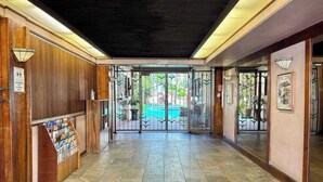 Eine Hotelhalle mit einer Rezeption, einem gefliesten Boden und einer Glastür zum Ausgang.