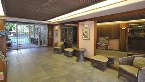 Eine Lobby mit Korbmöbeln, einer Rezeption, gerahmten Kunstwerken und einem Zeitschriftenständer.