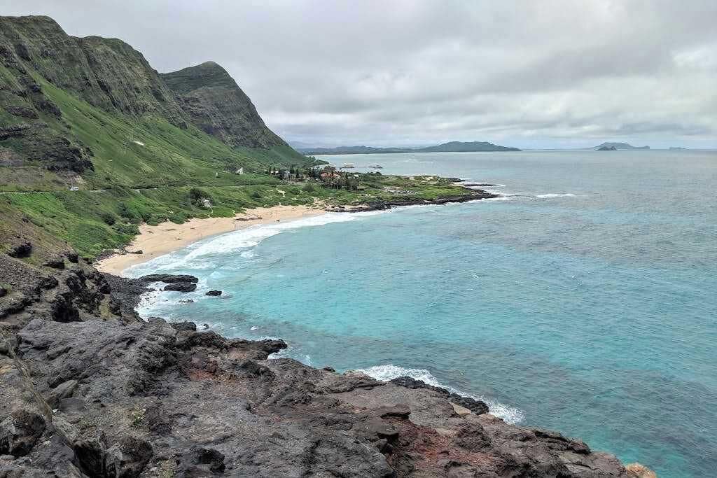 A coastal landscape with a beach, rocky cliffs, and a view of the ocean.