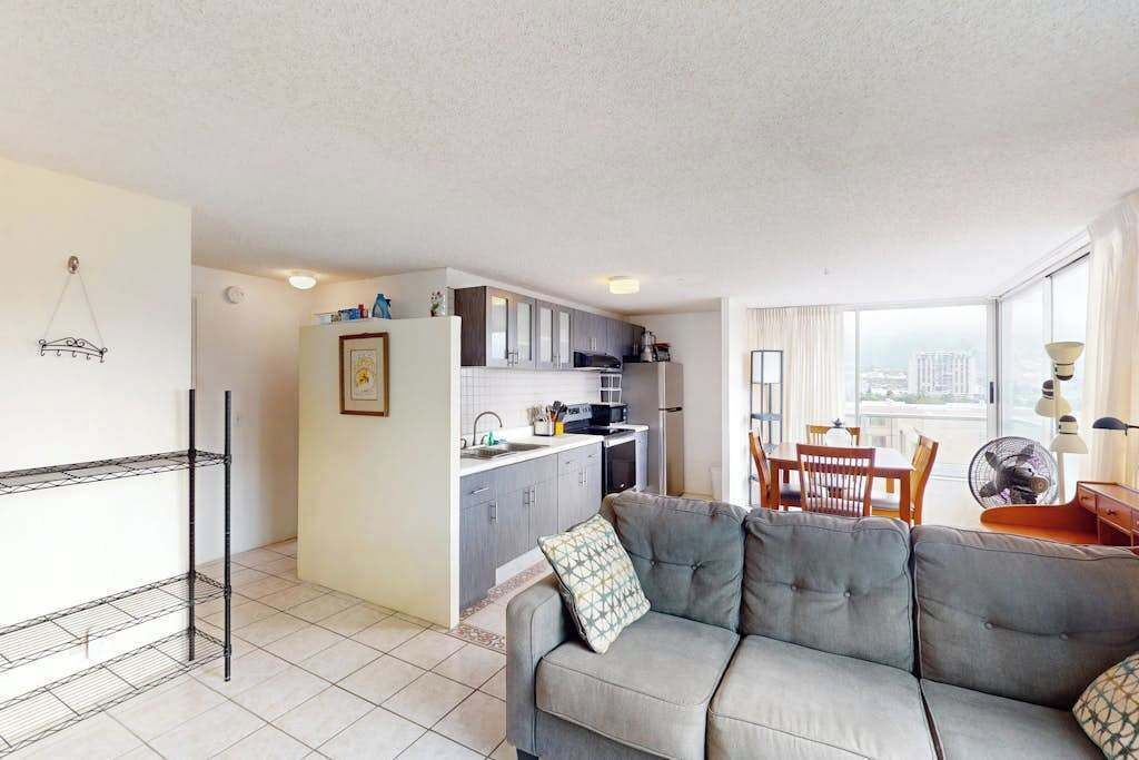 A compact living space with a kitchenette, a sofa, a dining table, and a view through large windows.