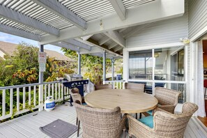 Un patio exterior techado con una mesa redonda y sillas de mimbre, una parrilla y un letrero que indica una zona tranquila.