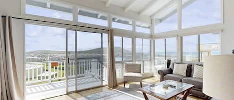 A spacious living room with large windows, a balcony, and a city view.