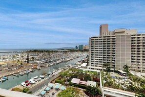 A marina with numerous boats, a large hotel building with multiple floors and balconies, and a clear view of the ocean. - NEW Marina Sunsets from an 11th-Floor Ilikai Studio (Honolulu)