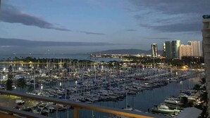 Een jachthaven met veel boten afgemeerd, een stadsachtergrond en een uitzicht vanaf een balkon.