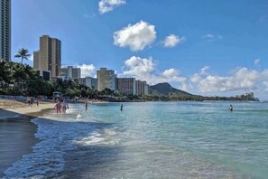 A beach with clear water, people walking, and tall buildings in the background. - NEW Waikiki Cottage by the Beach, Zoo and Kapiolani Park | 30 Nights (Honolulu)