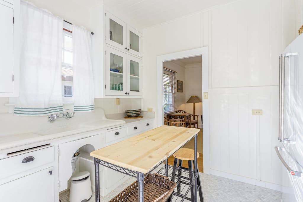 A compact kitchen with white cabinetry, a wooden table, and a built-in sink.