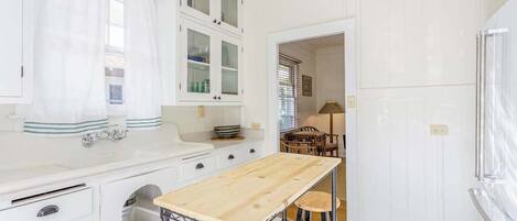 A compact kitchen with white cabinetry, a wooden table, and a built-in sink.