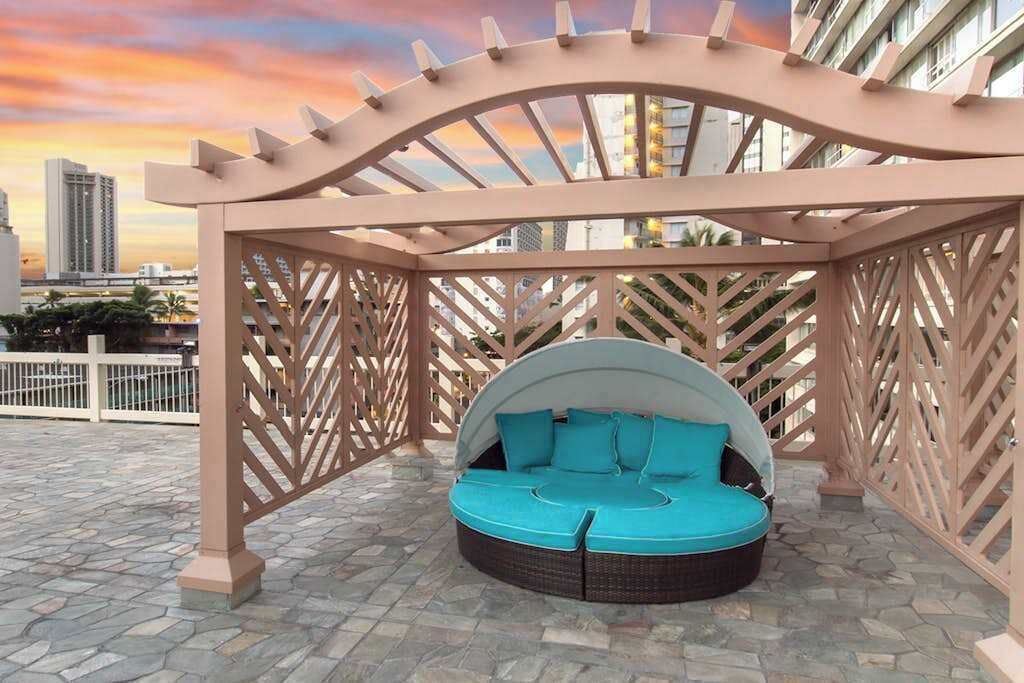 A circular outdoor seating area with a canopy, surrounded by a lattice structure.
