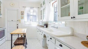 A kitchen with white cabinets, a wooden table, and a white sink. - *NEW* Diamond Head Cottage Near Waikiki, 30-Night Minimum (Honolulu)