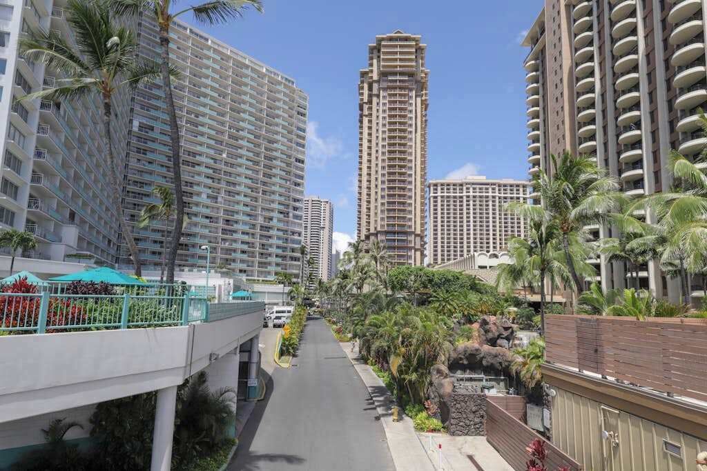 A multi-story hotel with balconies, a central walkway, and palm trees.
