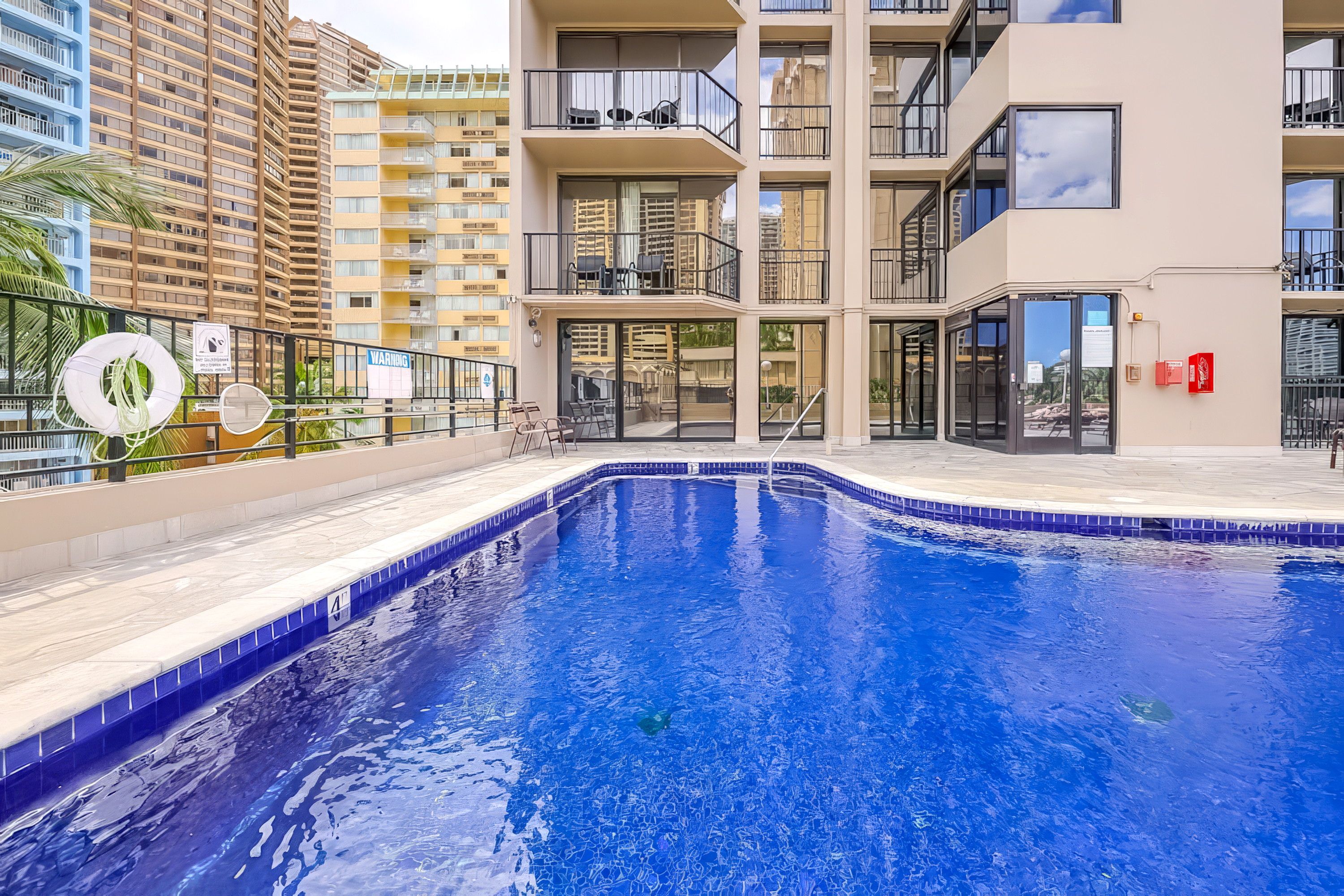 Una piscina con borde curvo, rodeada por un balcón con mobiliario de exterior.
