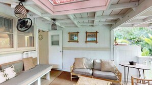 Una habitación acogedora con una banca, sofá y mesa, que presenta techo de madera y cuadros en la pared.
