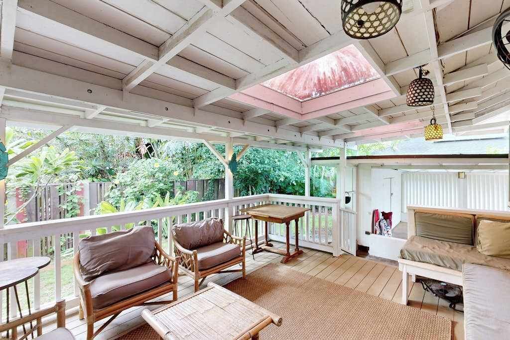 A covered outdoor area with wooden furniture, a table, and a sofa.