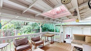 Un espacio al aire libre techado con muebles de madera, una mesa y un sofá.